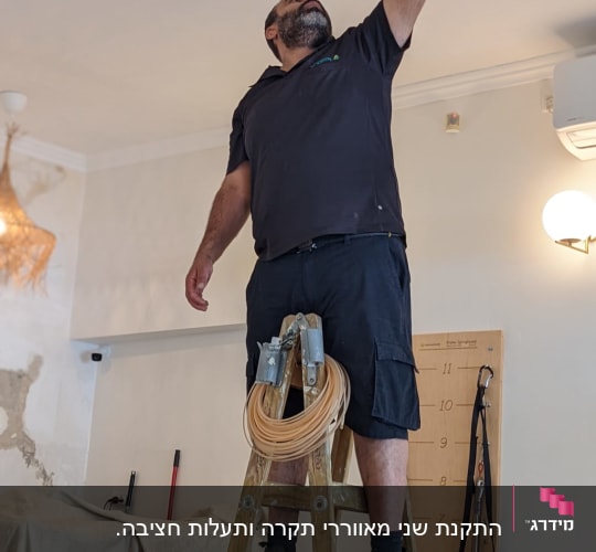 חשמלאי עומד על סולם עם כלי עבודה ביד